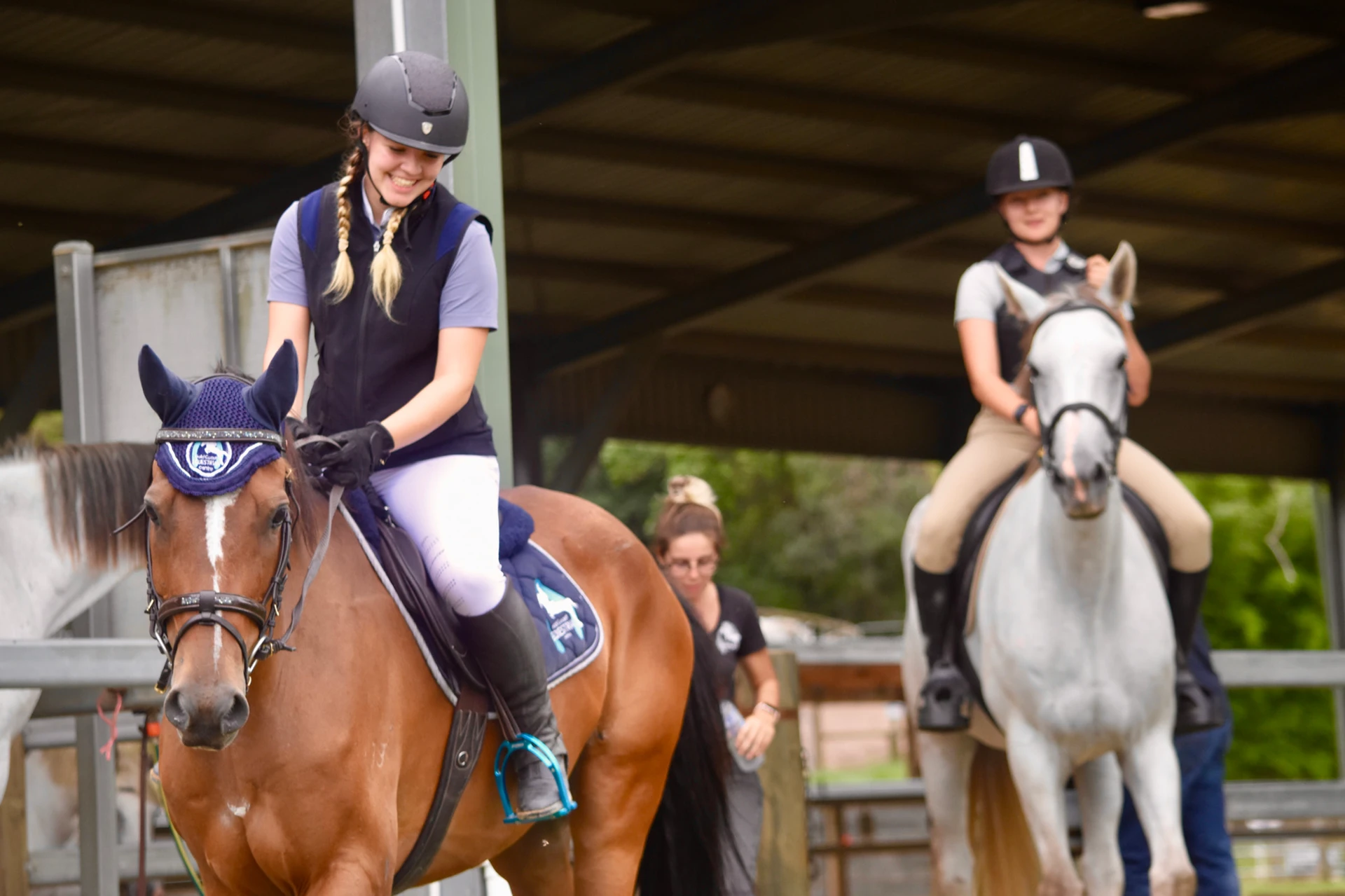 Two riders in the covered arena