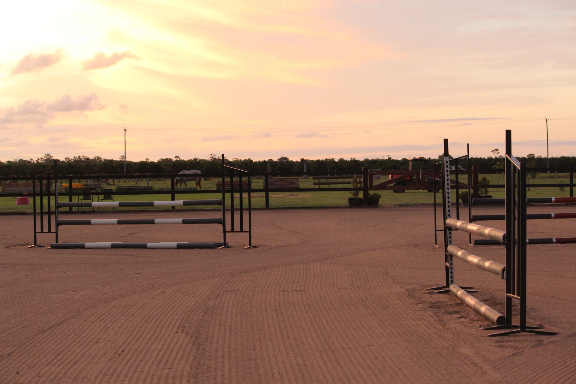 Show jumps set up in the sand arena at sunset